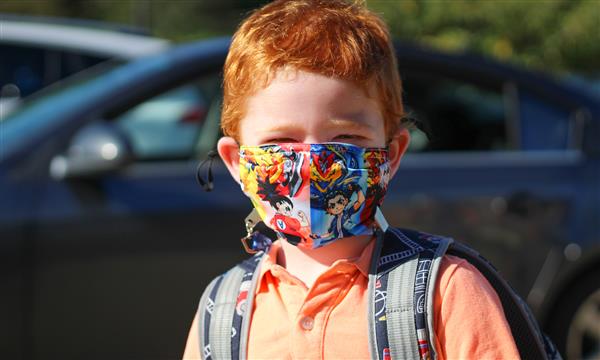 boy smiles while wearing mask